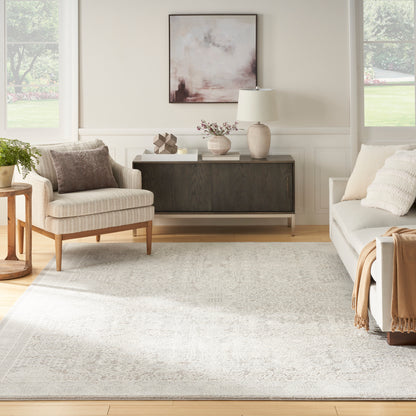 Bright living room with beige walls, neutral sofa & chair, dark wood sideboard, and a soft pink-gray abstract rug (6' x 9').