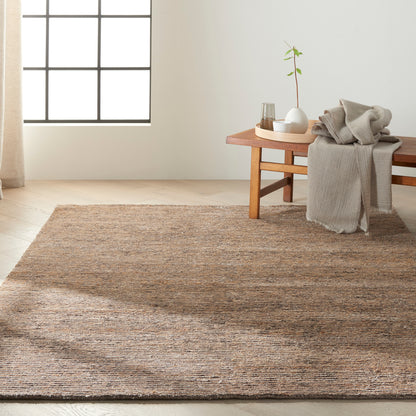 Natural brown textured jute rug in a cozy living space with beige throw on a wooden bench and a potted plant.