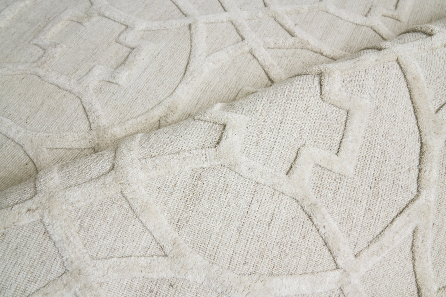 Cream geometric area rug close-up with raised plush lines forming angular interlocking shapes.