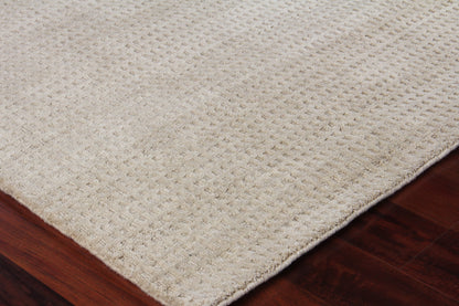 Beige rectangular rug with textured woven loop pattern on dark hardwood floor.