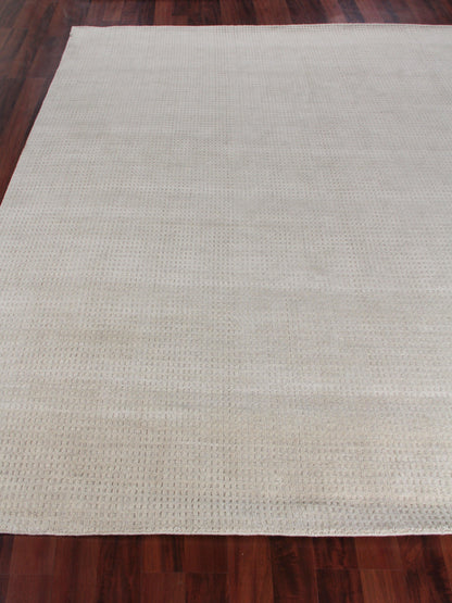 Beige rectangular woven rug with a subtle dotted texture on a dark wooden floor.