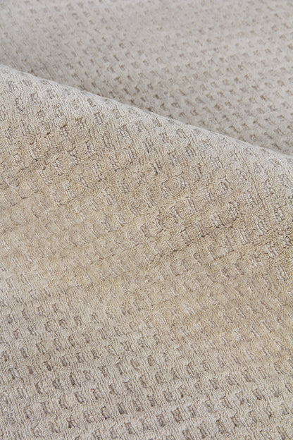 Beige close-up of a waffle-knit New Zealand wool rug with soft folds; textured, neutral rug.