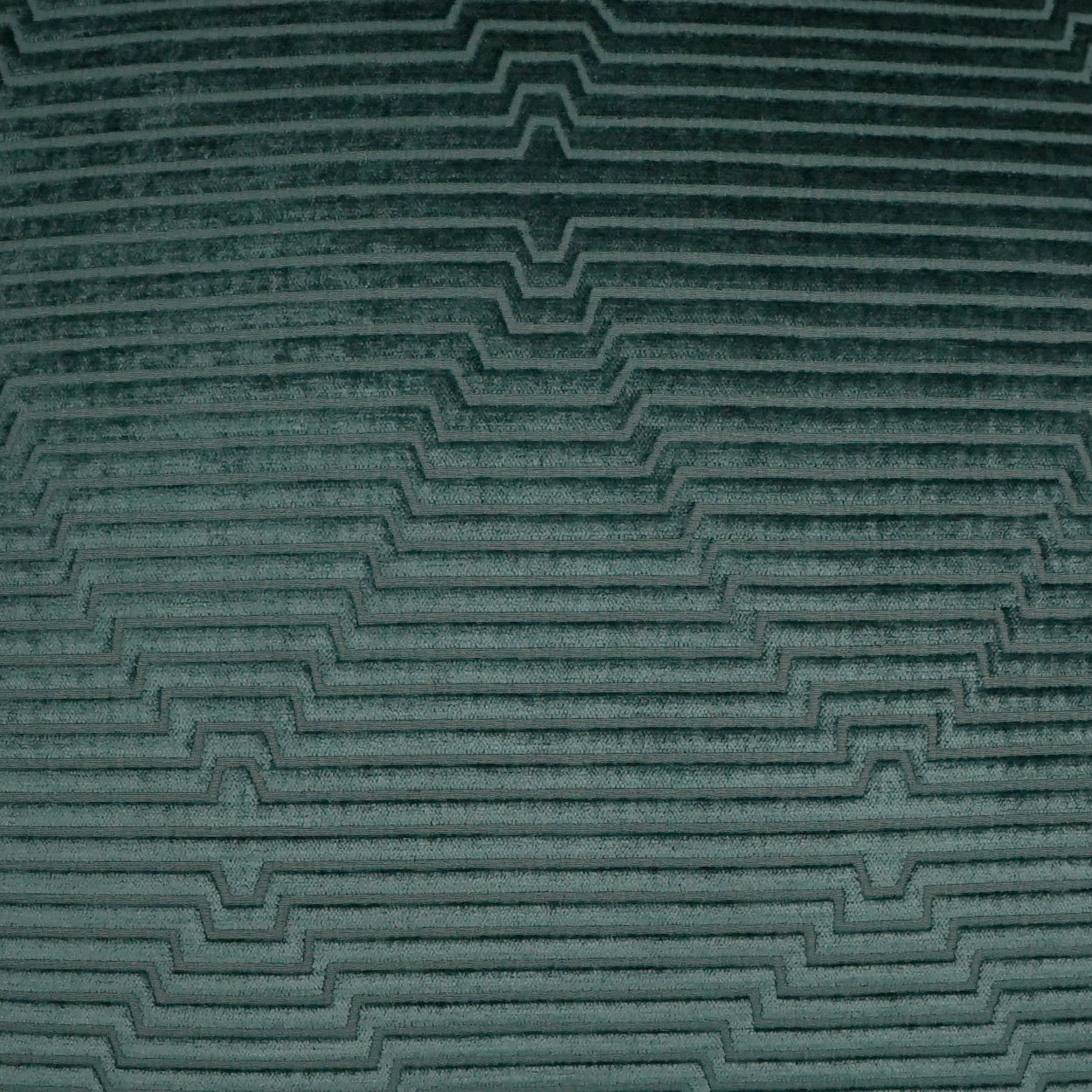 Teal fabric close-up with raised stepped chevron pattern.