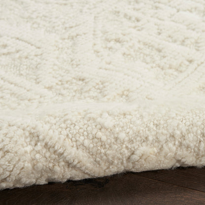 Ivory shag rug with chunky plush pile on dark wood floor, edge visible, cozy living room decor.
