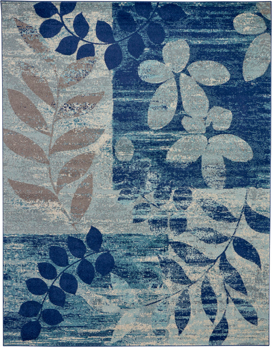 Blue-toned area rug with abstract leaf motif in navy, teal and beige on a textured backdrop.