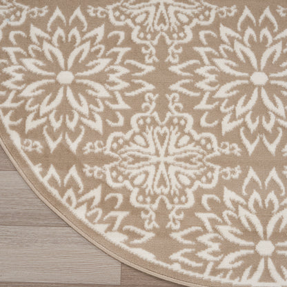 Round beige rug with white geometric floral medallion pattern on light wood floor.
