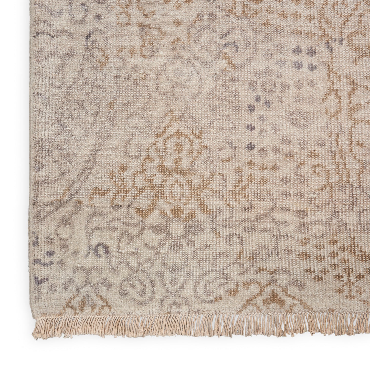Muted beige and gray ornate rug with floral motifs and fringe along the edge; woven floor decor.