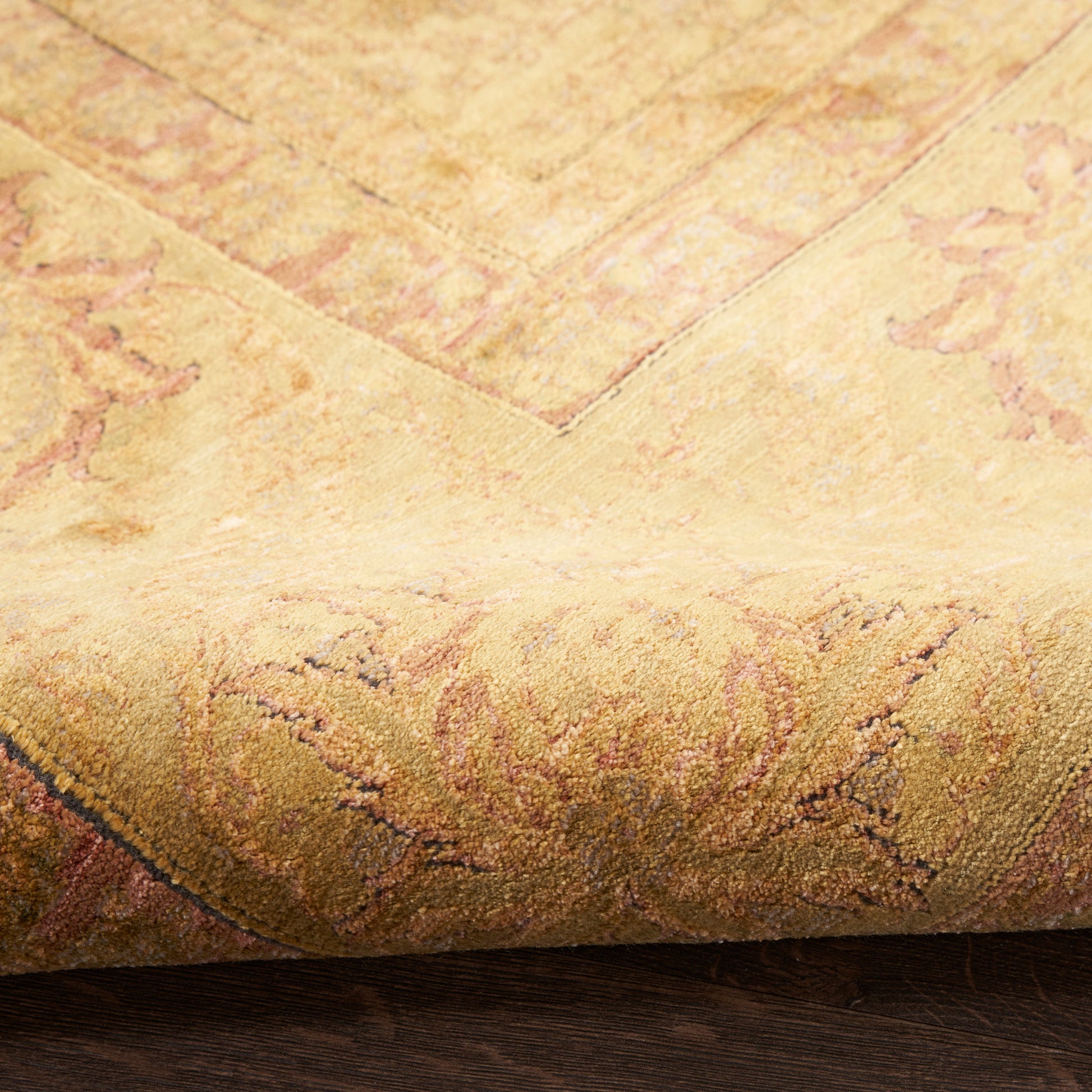 Beige gold oriental rug with floral pattern, rolled edge showing soft pile and decorative border.