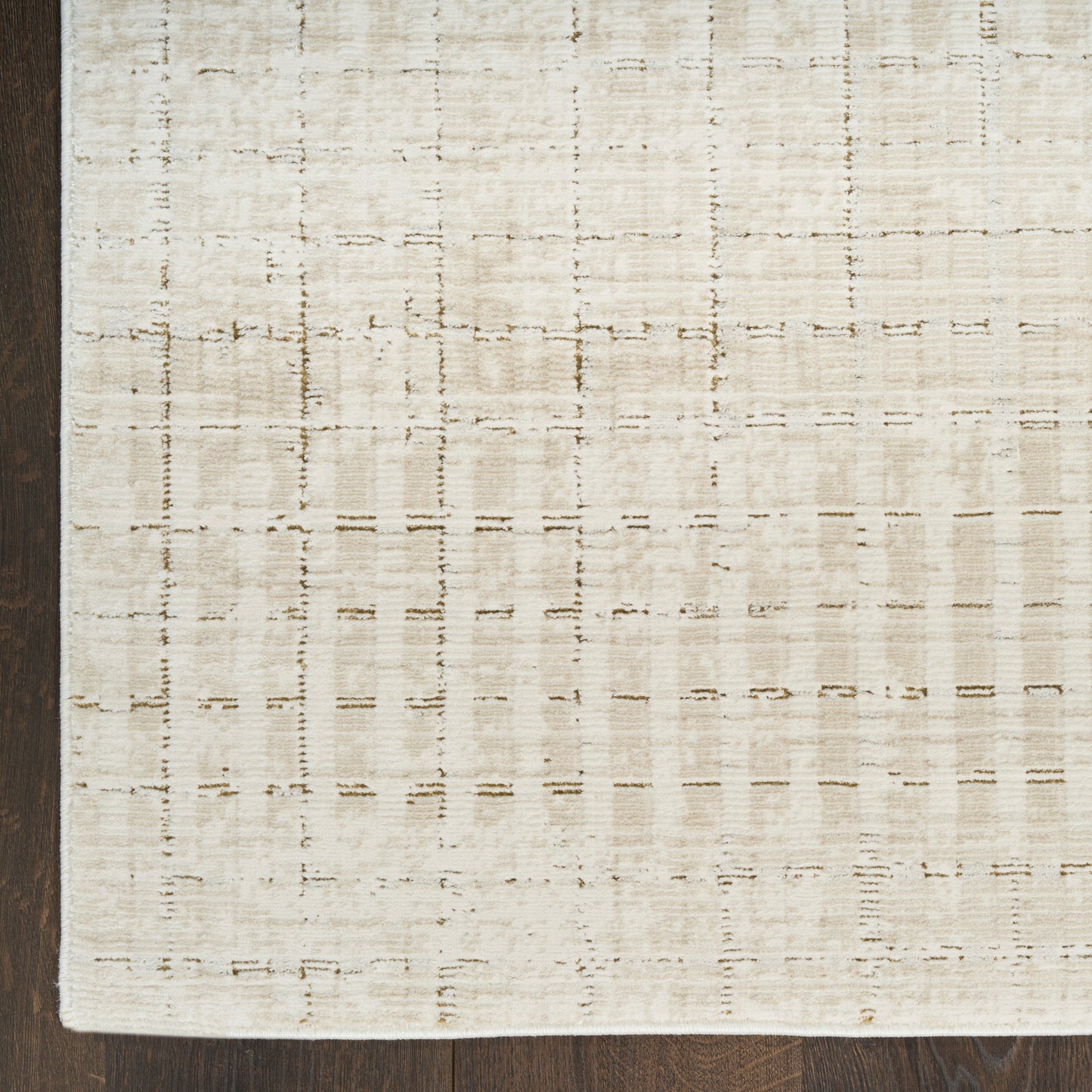 Beige flat-weave rug with subtle grid pattern on dark wooden floor.