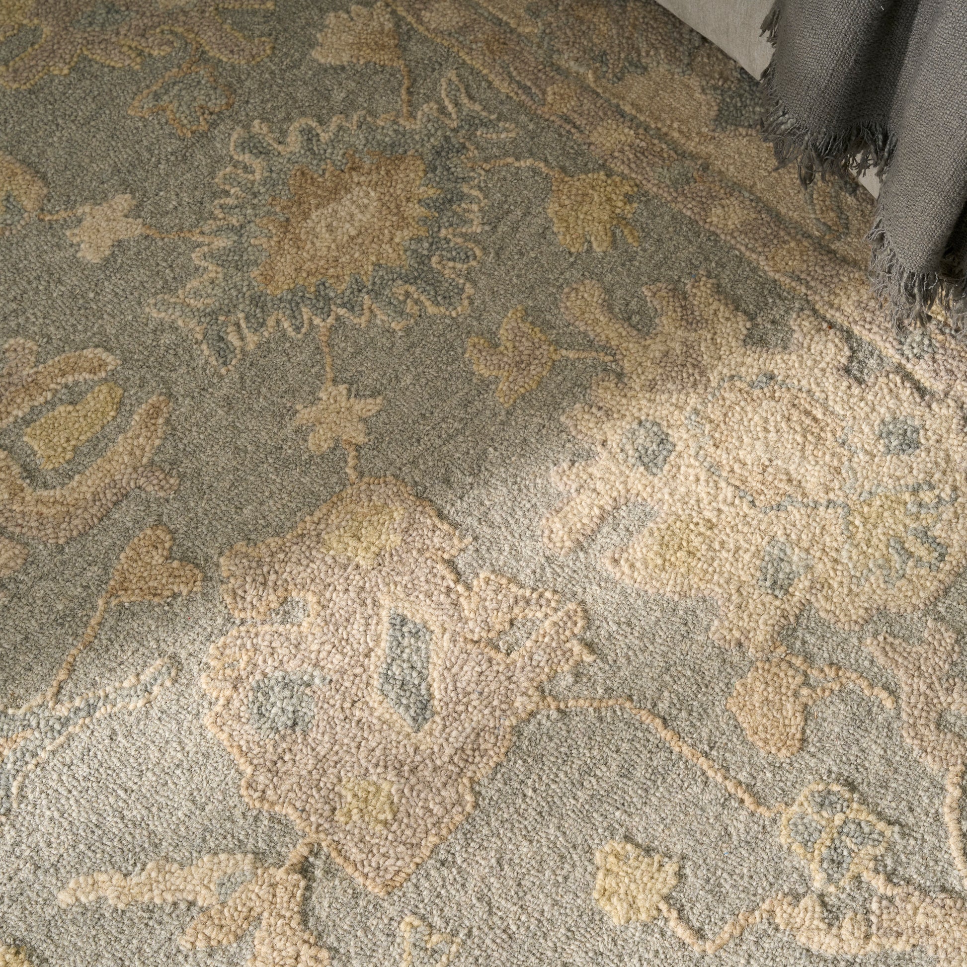 Gray traditional rug with beige, cream and pale yellow floral medallion pattern; soft textured pile, fringe at edge.