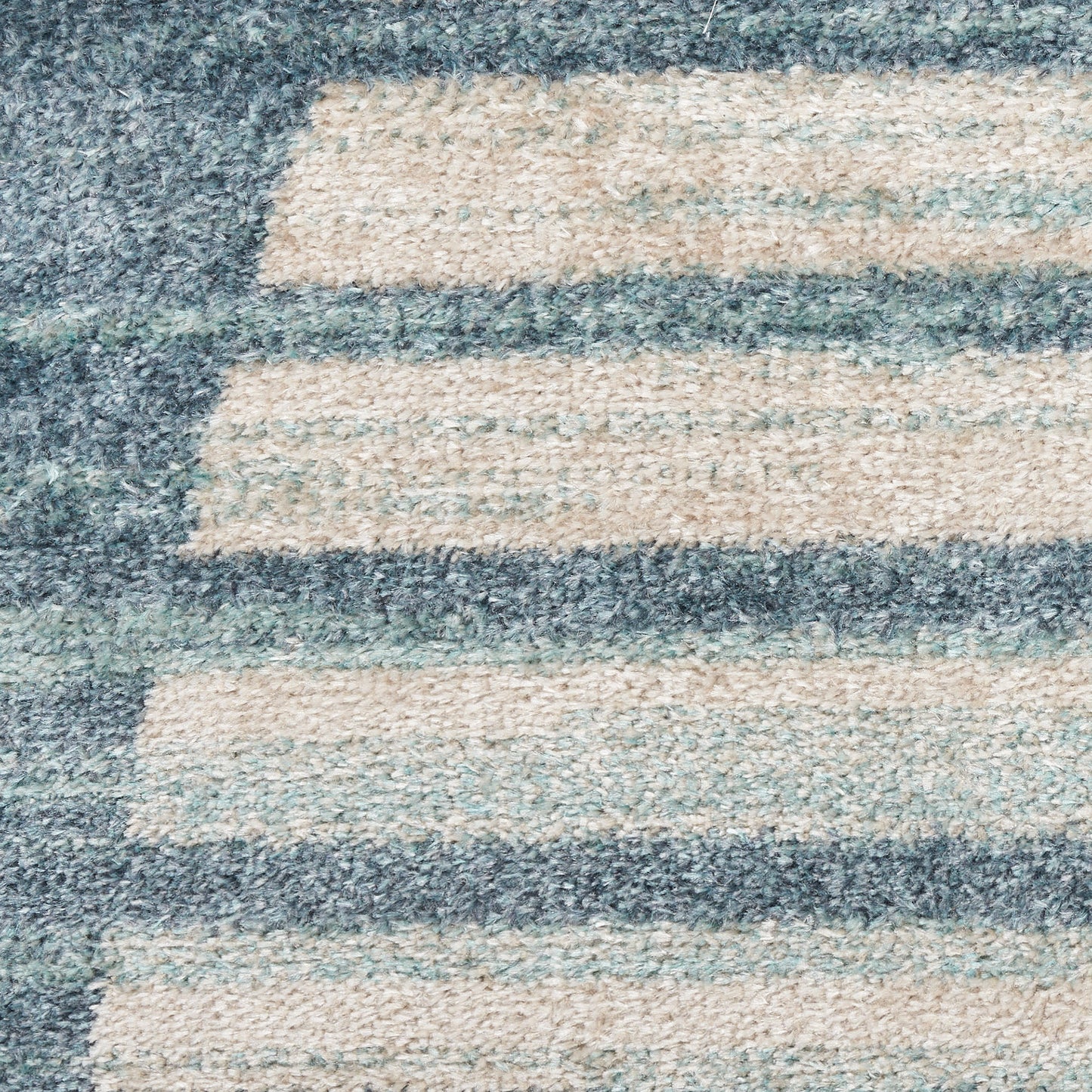 Close-up of a blue-gray and beige striped shag rug with plush pile.