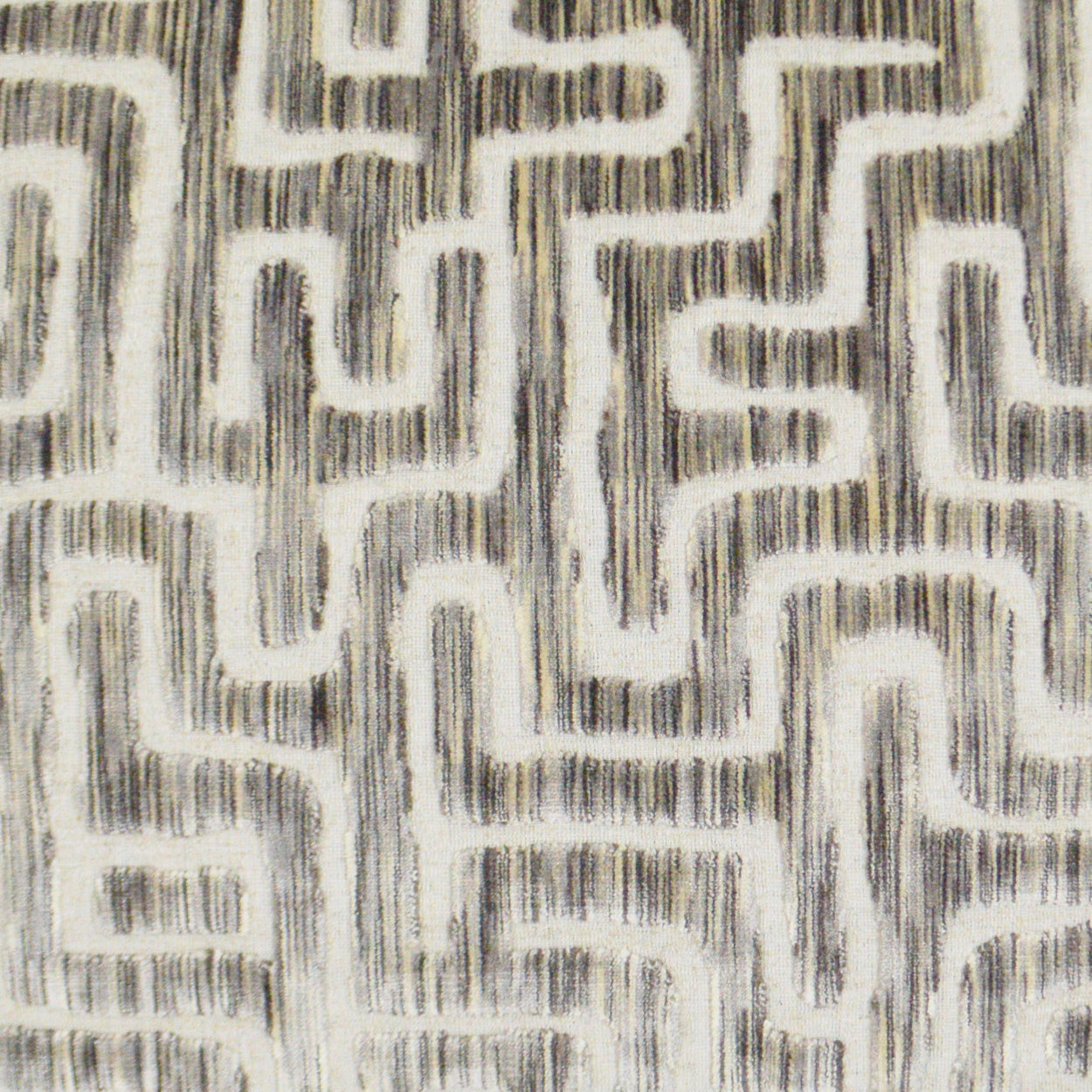 Beige pillow with a dark gray, maze-like geometric pattern and brushed texture.