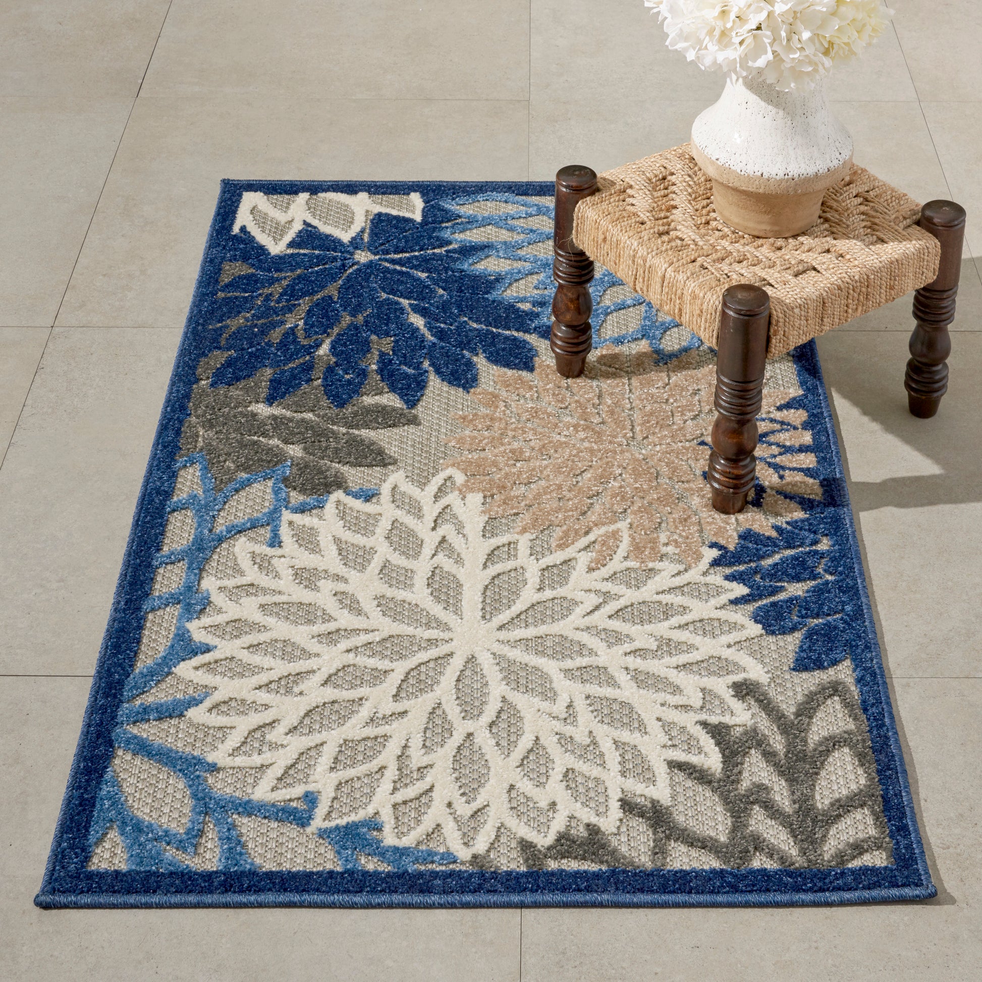 Blue-bordered tropical rug 3' x 4' with oversized white floral petals and beige-gray accents.