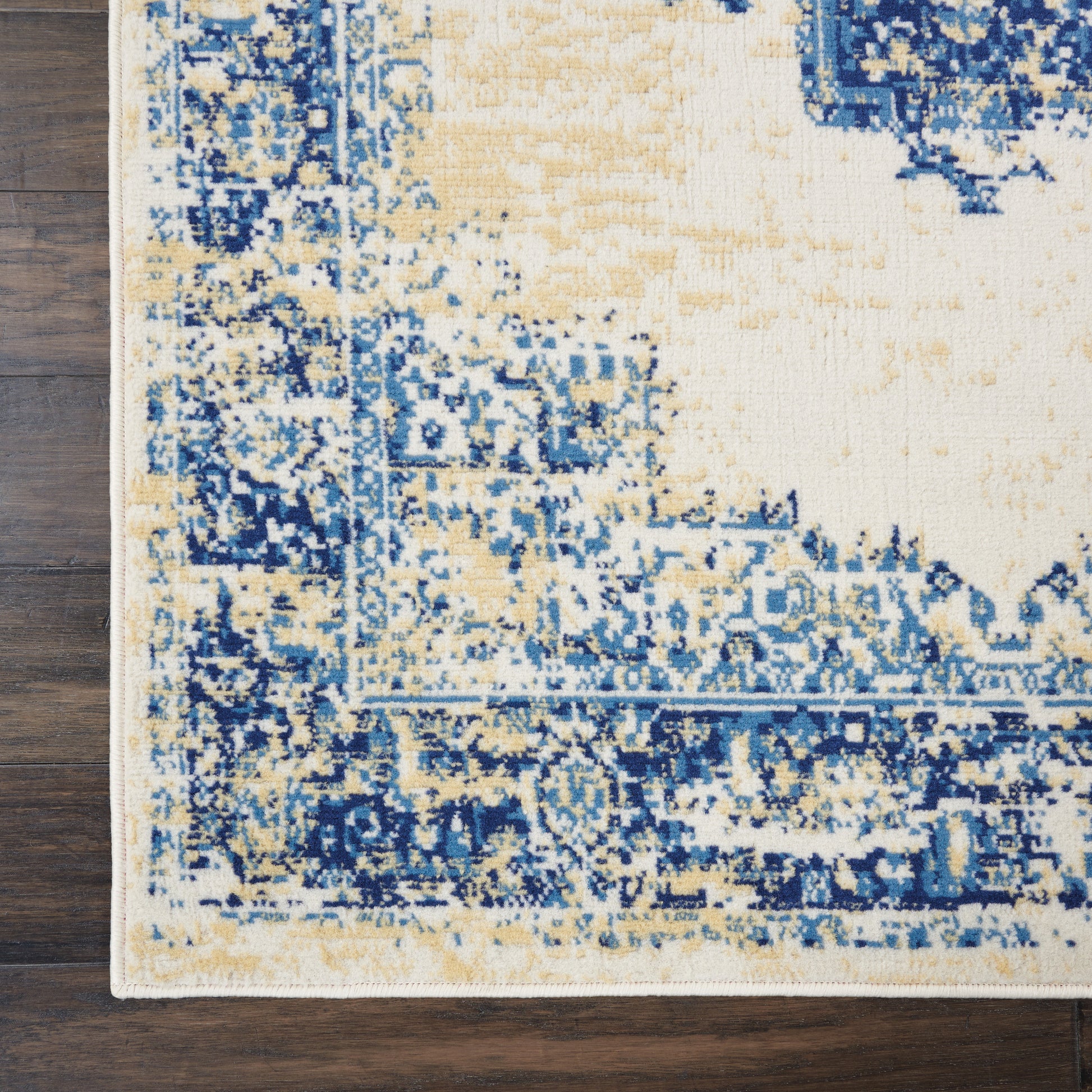 Rectangular distressed-pattern rug in blue, ivory & beige with ornate border on dark wood floor.