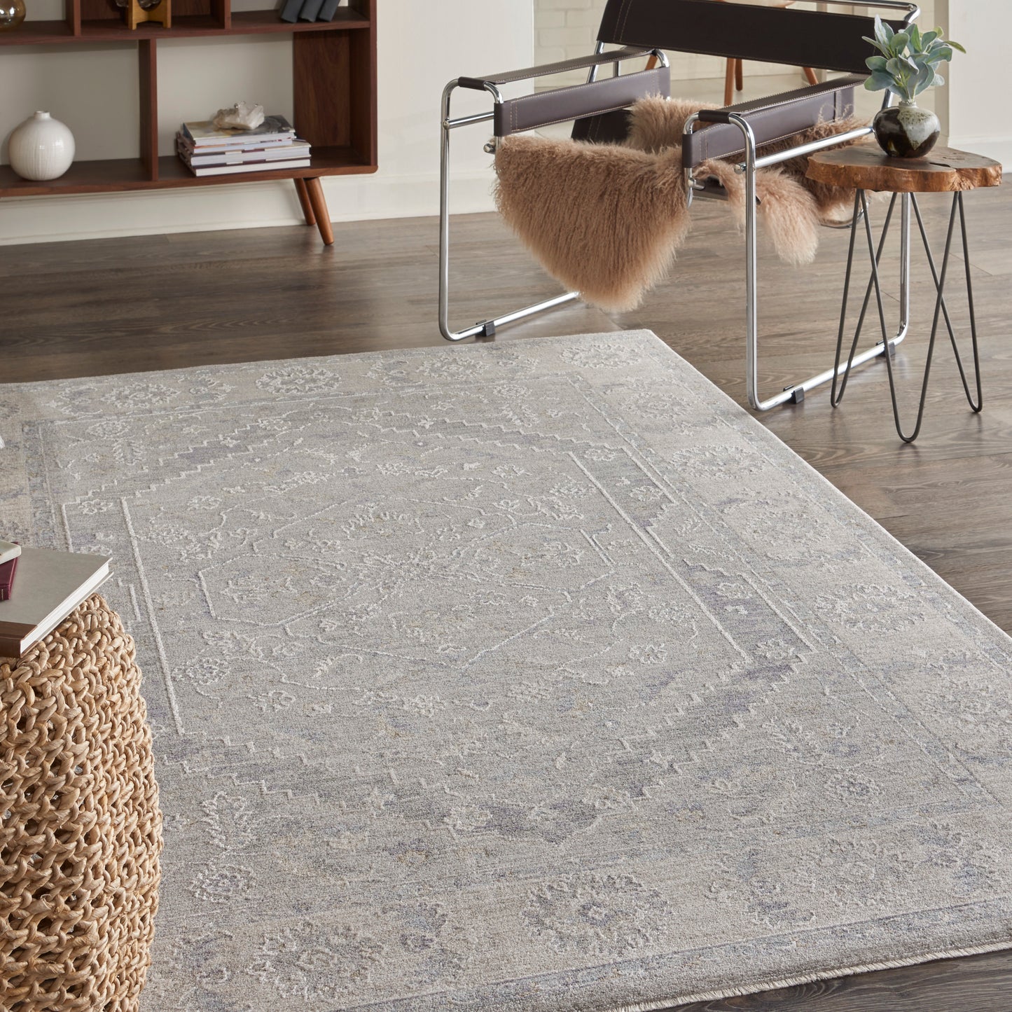 Soft gray patterned area rug with ivory motifs on dark wood floors in a modern living room.