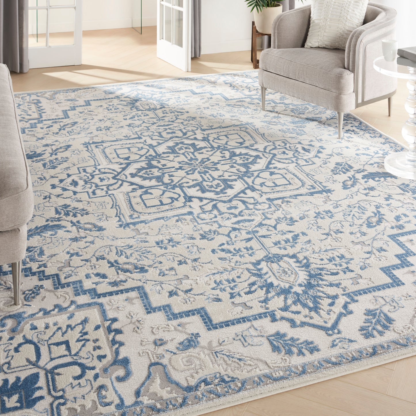 Blue and cream oriental-style area rug with medallion center and geometric border in a bright living room.