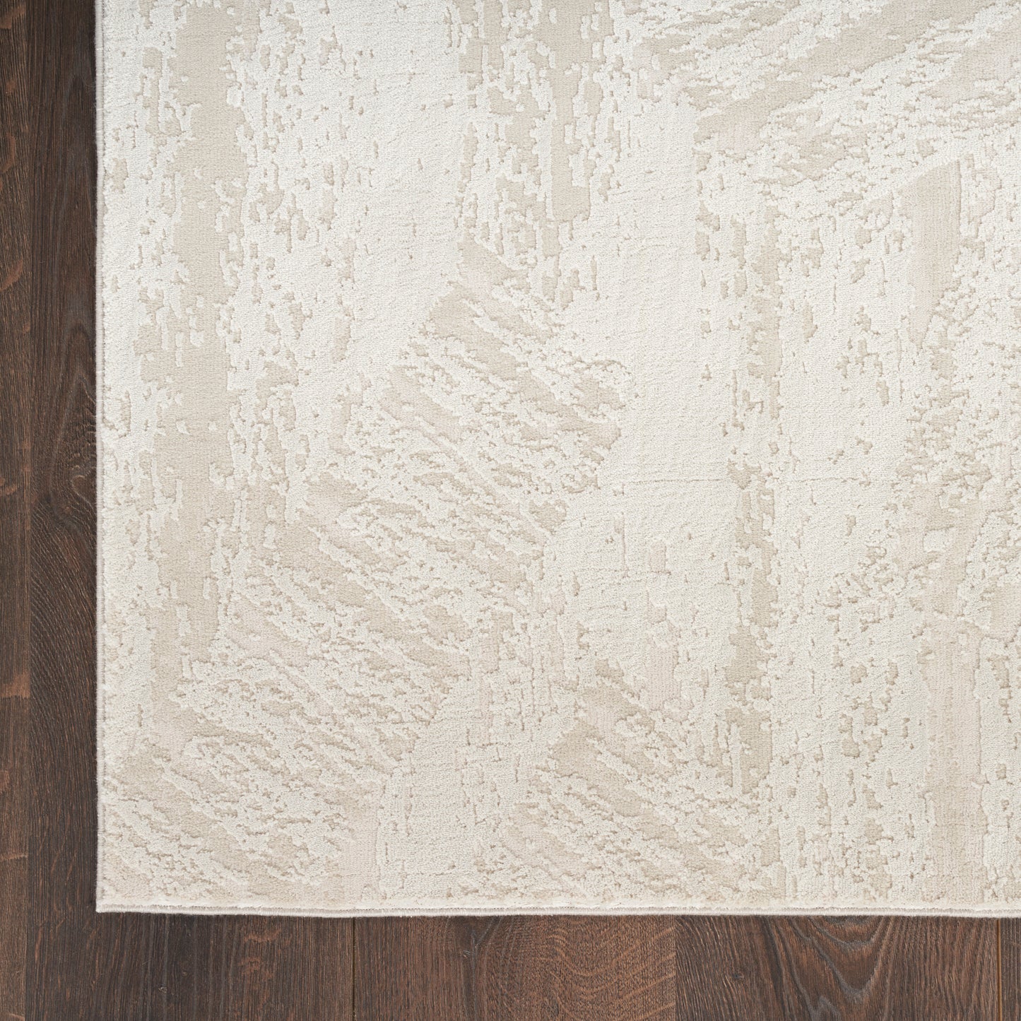 Rectangular beige textured area rug with subtle abstract pattern on dark hardwood floor.