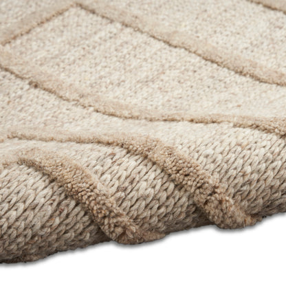 Beige chunky knitted rug with braided edge, plush pile and subtle chevron pattern for cozy living space.