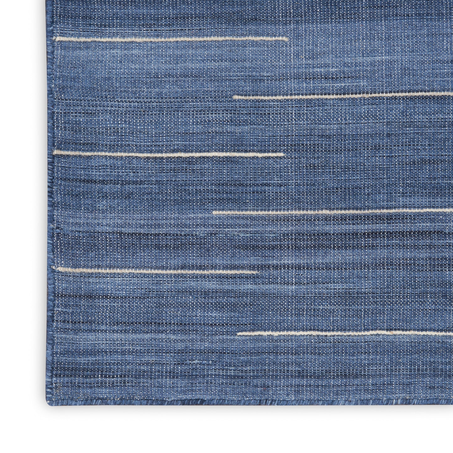 Blue denim rug close-up with multiple white contrast stitches running horizontally.