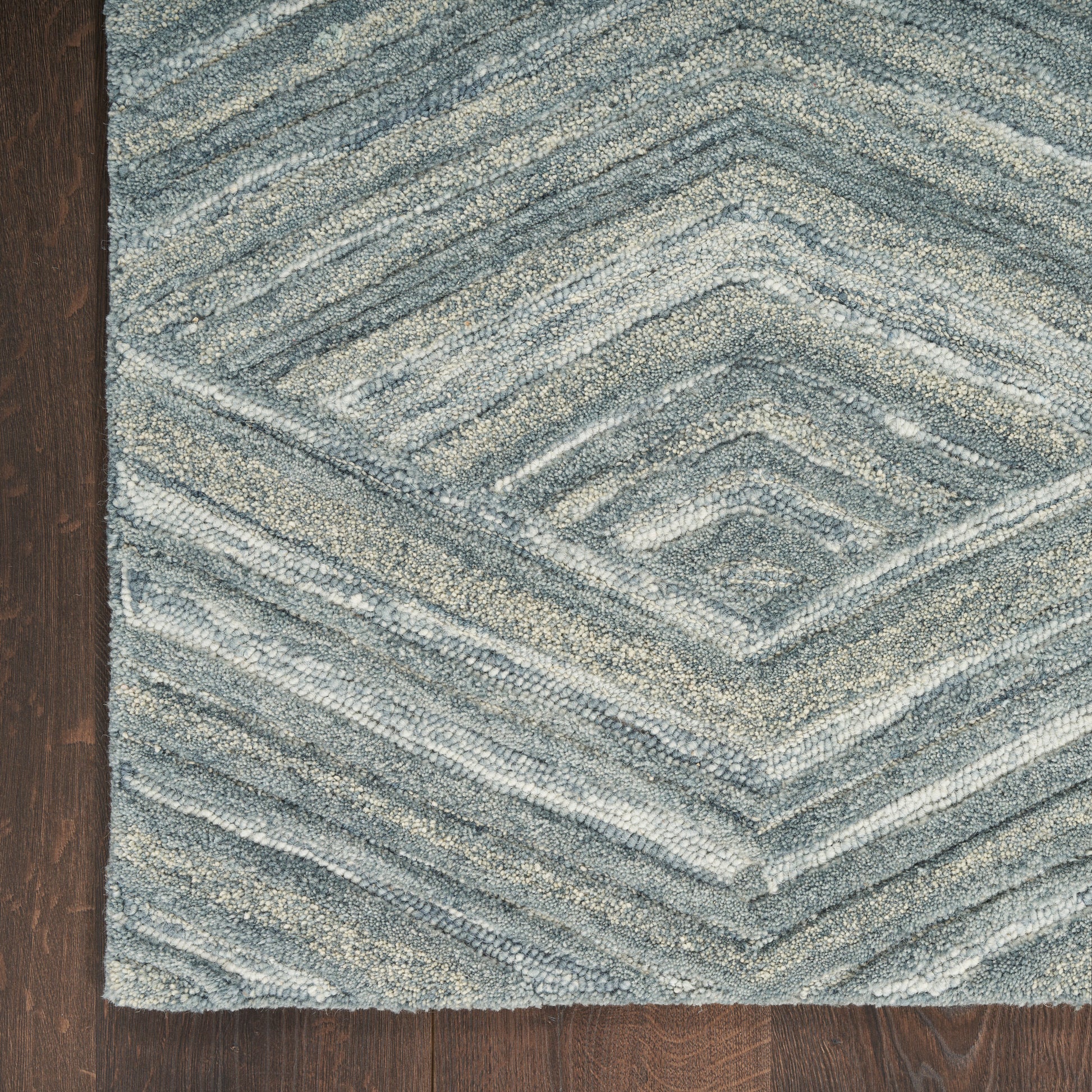Blue-gray textured rug with a chevron diamond pattern on dark wood floor.