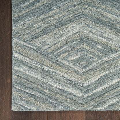Blue-gray textured rug with a chevron diamond pattern on dark wood floor.