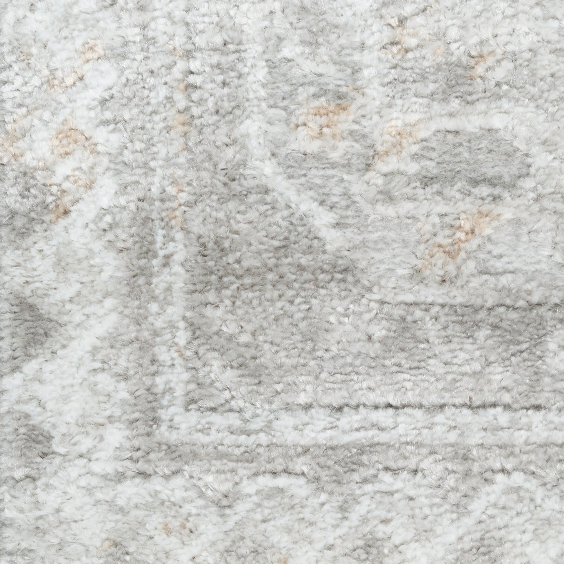 Light gray shag rug close-up with cream accents and soft pile; subtle border pattern.
