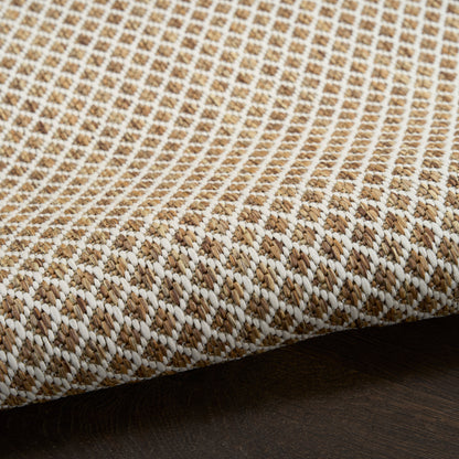 Beige and white woven textile rug with a tight diagonal pattern and folded edge on dark wood surface.