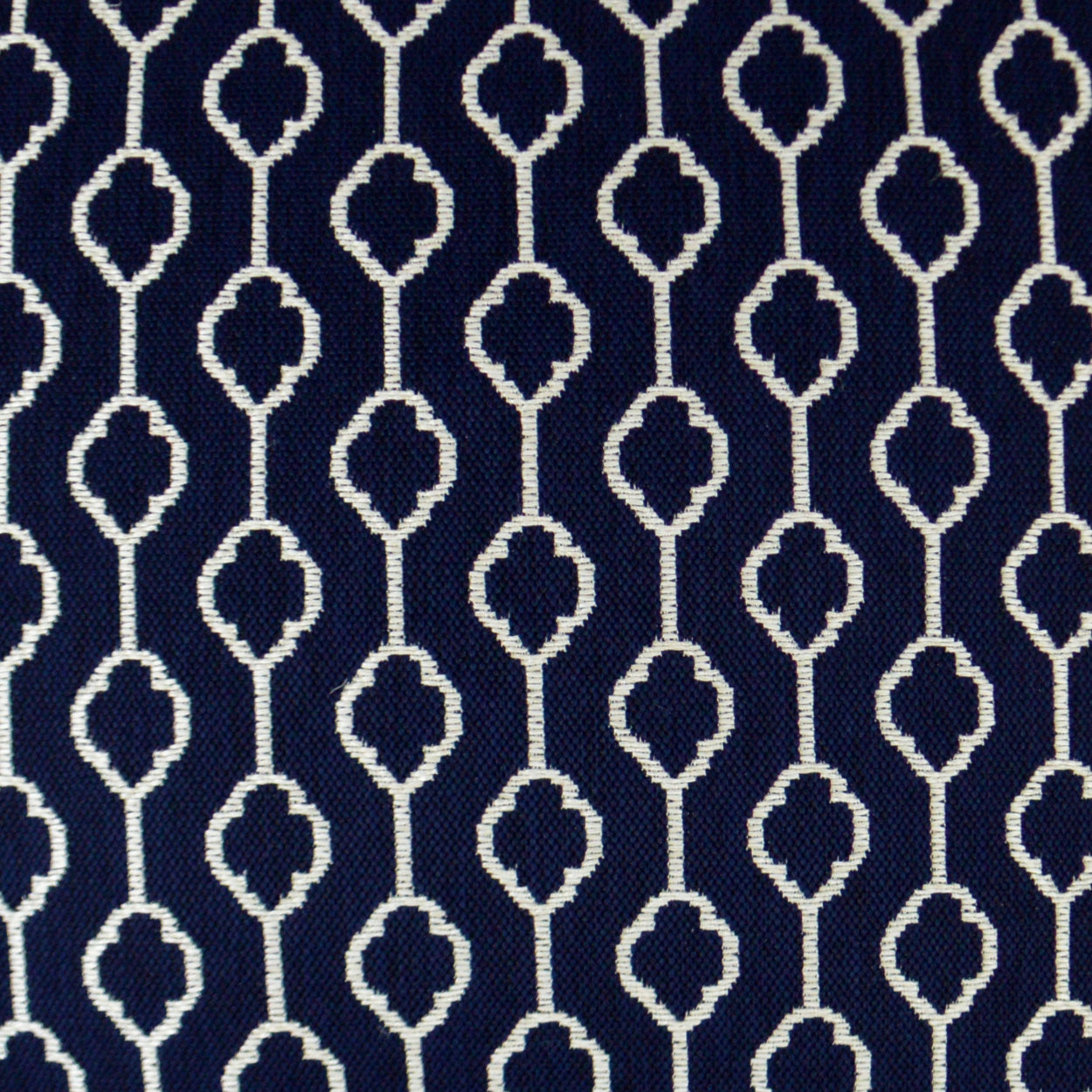 Navy fabric with white repeating geometric lattice and clover-like motifs.