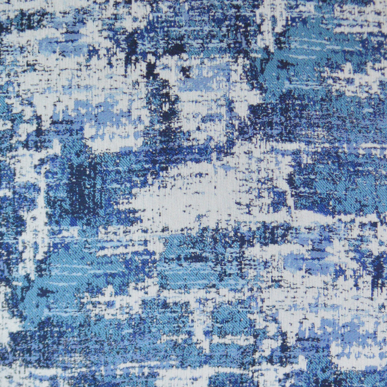 Abstract blue and white woven fabric with distressed painterly pattern.