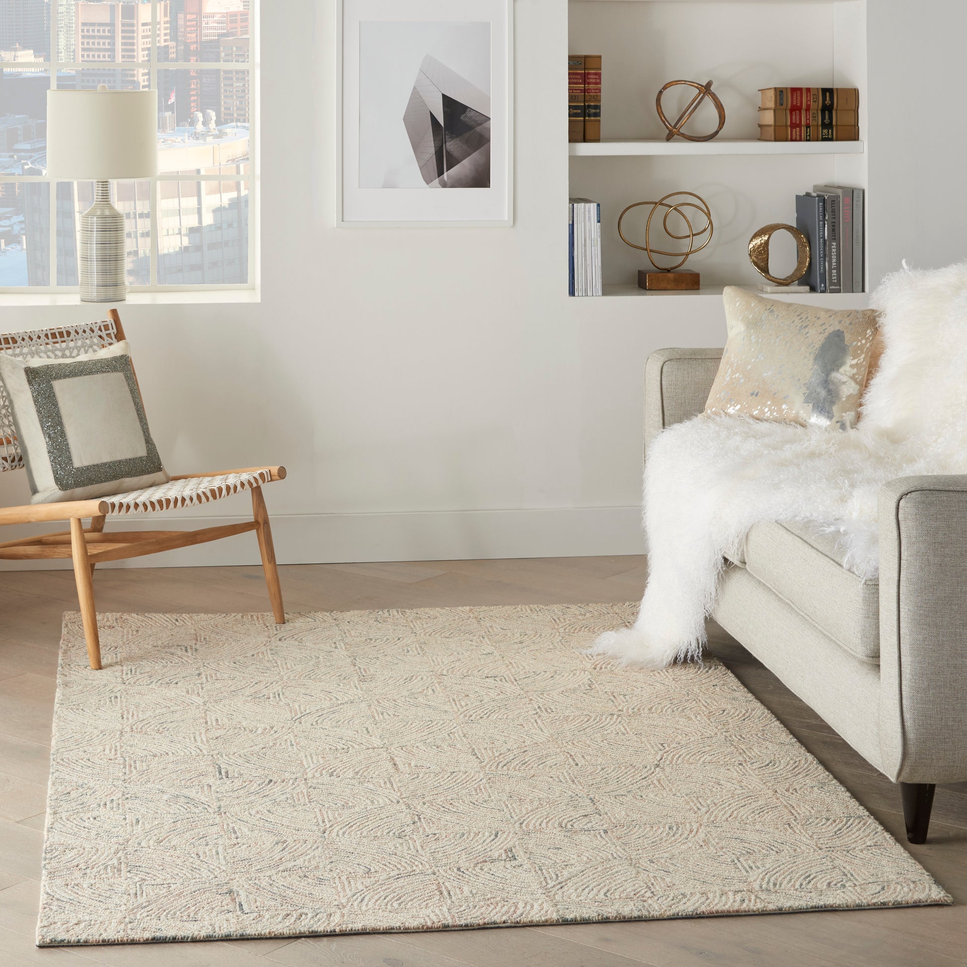 Bright neutral living room with a beige sofa, fluffy white throw, woven rug, wooden lounge chair, and built-in shelves.