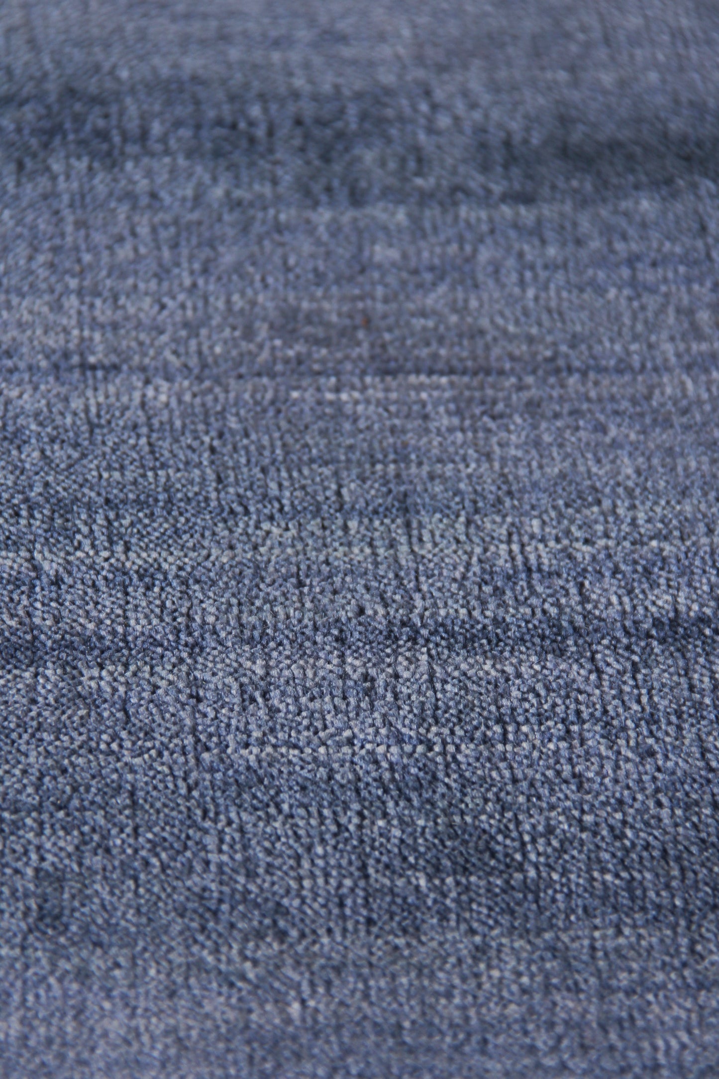 Close-up of blue denim-like rug with textured twill weave in medium indigo, rugged casual style.
