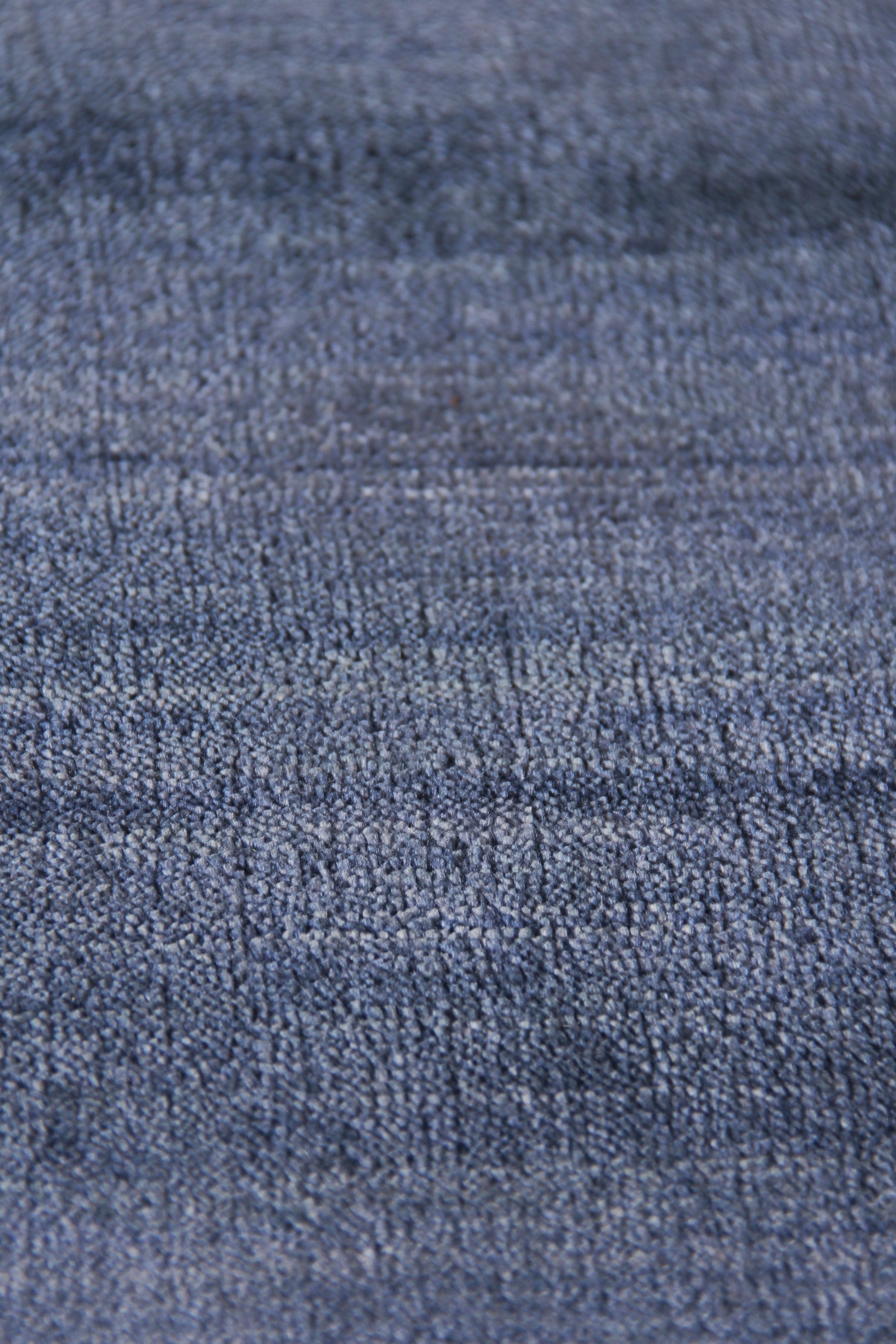 Close-up of blue denim-like rug with textured twill weave in medium indigo, rugged casual style.