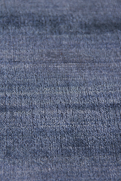 Close-up of blue denim-like rug with textured twill weave in medium indigo, rugged casual style.