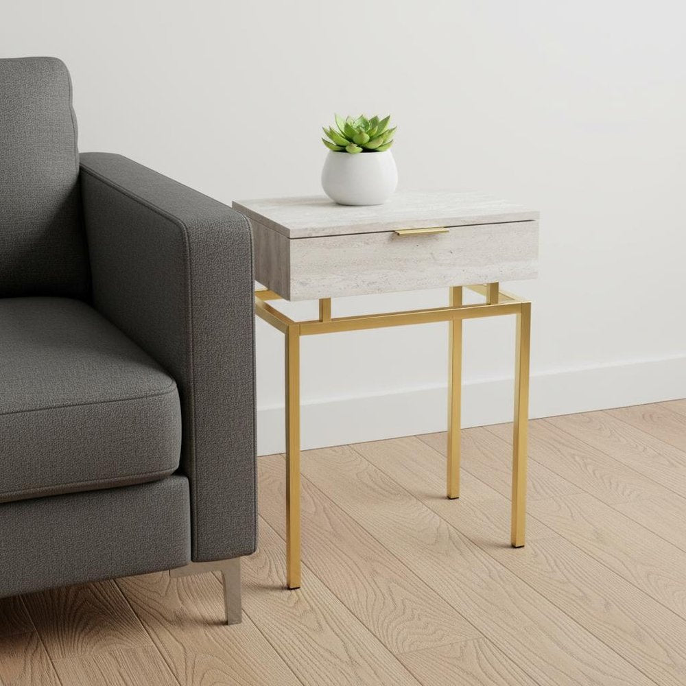 Modern side table with pale wood drawer and gold metal legs beside a gray sofa, topped by a white succulent planter.