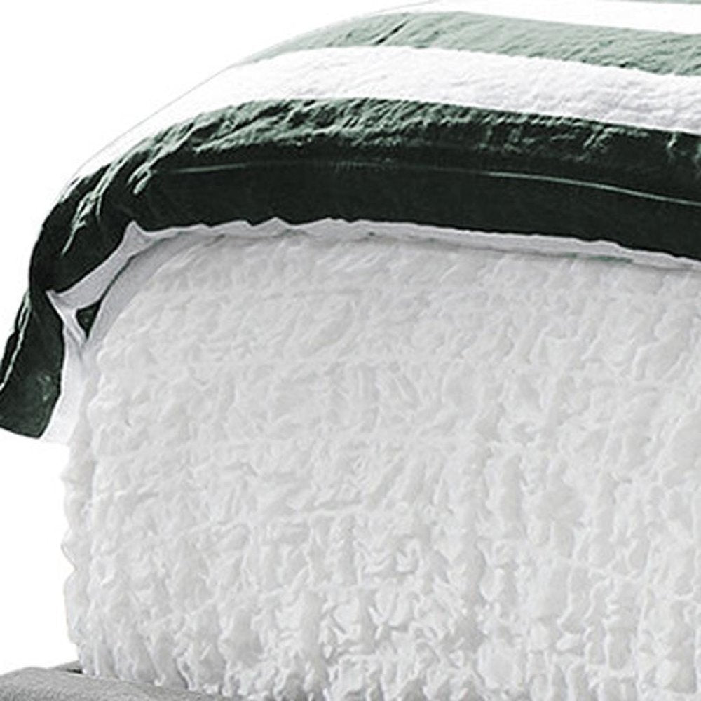 White textured quilt with a dark green and black striped border, cozy bedspread.