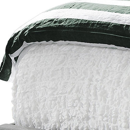 White textured quilt with a dark green and black striped border, cozy bedspread.