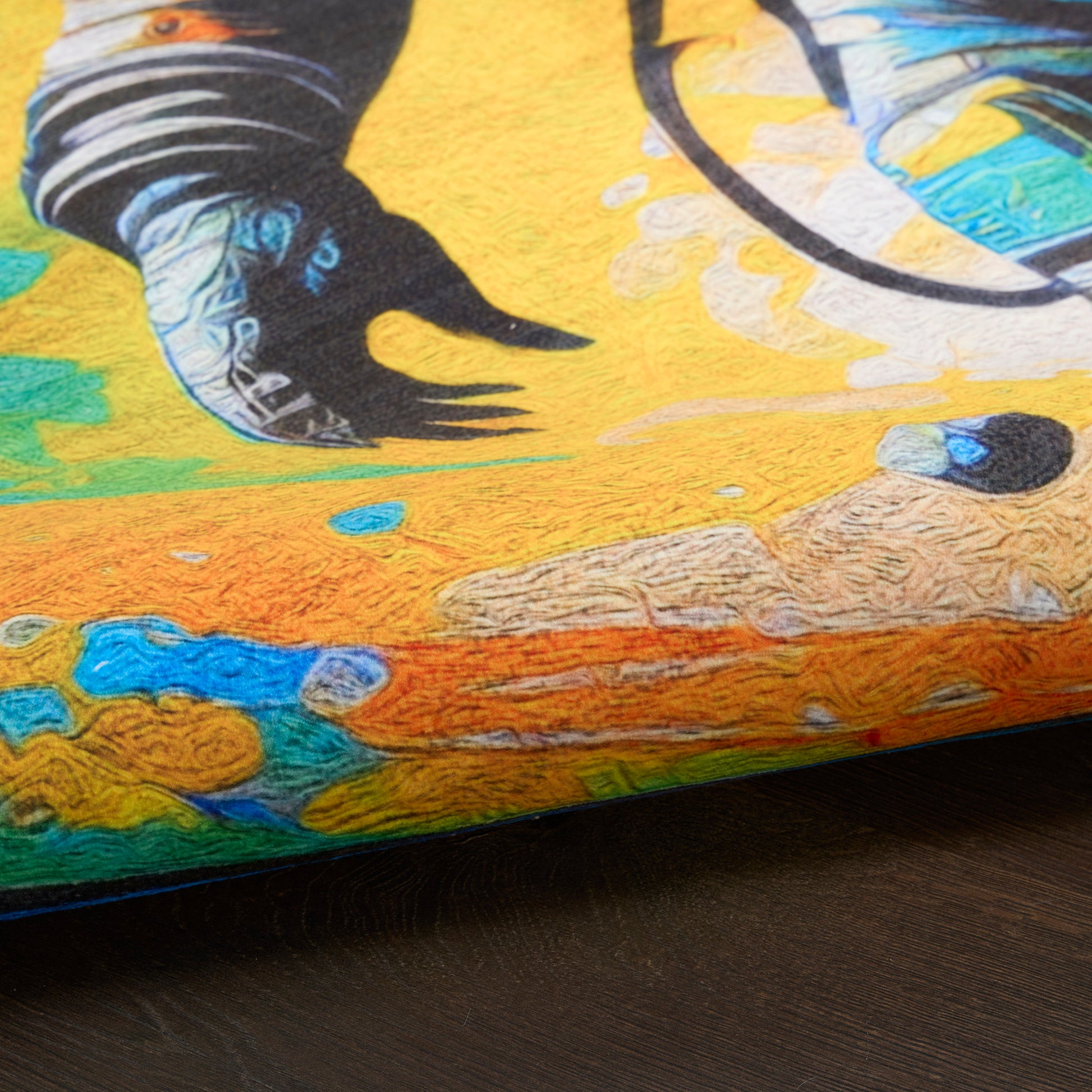 Close-up of graffiti-style print on textured surface with bright yellow and orange, blue/green accents, blue trim along edge.