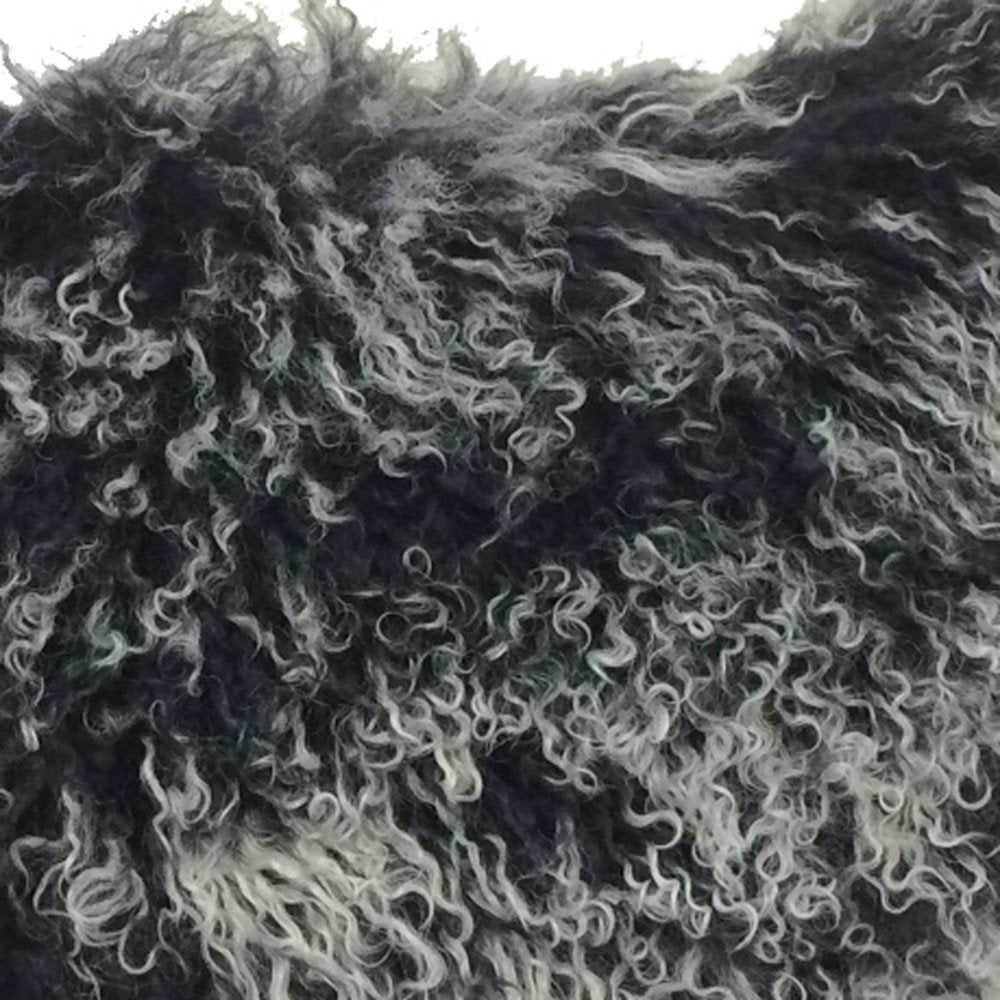 Close-up of black Tibetan lamb fur on a 17-inch pillow with microsuede backing; dense, plush, curly fur.