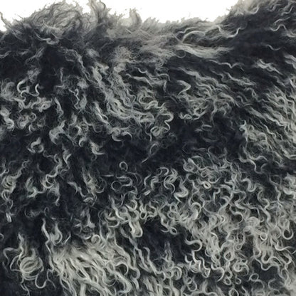 Close-up of black Tibetan lamb fur on a 17-inch pillow with microsuede backing; dense, plush, curly fur.