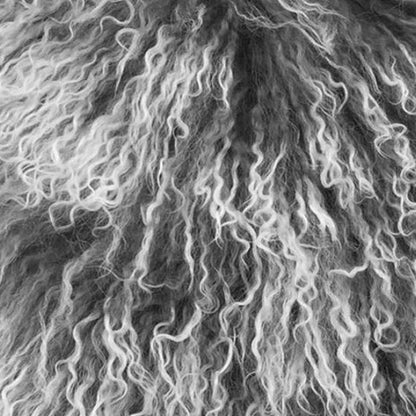 Close-up of soft, curly grey Tibetan lamb fur on a pillow with microsuede backing.