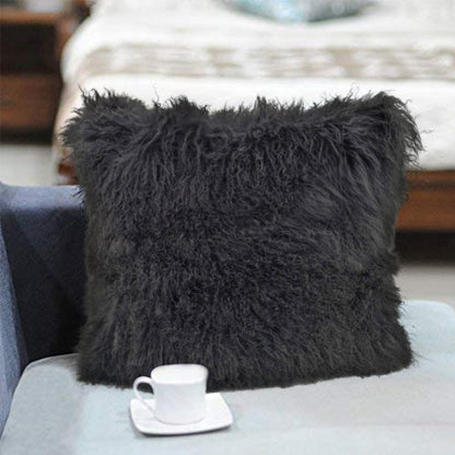 Charcoal 24" genuine Tibetan lamb fur pillow with microsuede backing on a pale sofa.