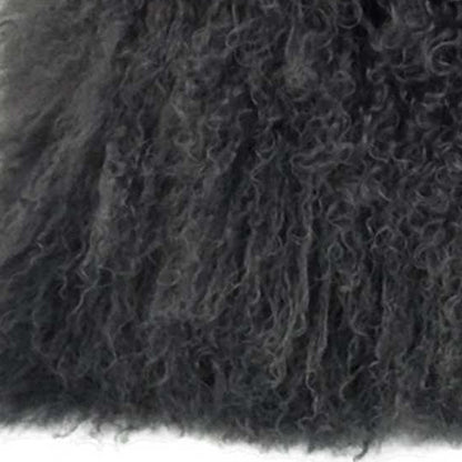Close-up of charcoal Tibetan lamb fur on a pillow; dense, curly fur texture with microsuede backing.