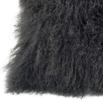 Close-up of charcoal Tibetan lamb fur on a pillow with microsuede backing; long curly pile, soft and plush.