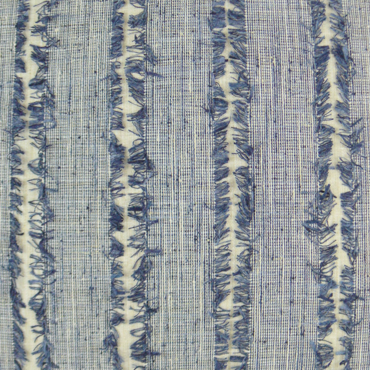 Blue striped woven fringe pillow on a cream background.