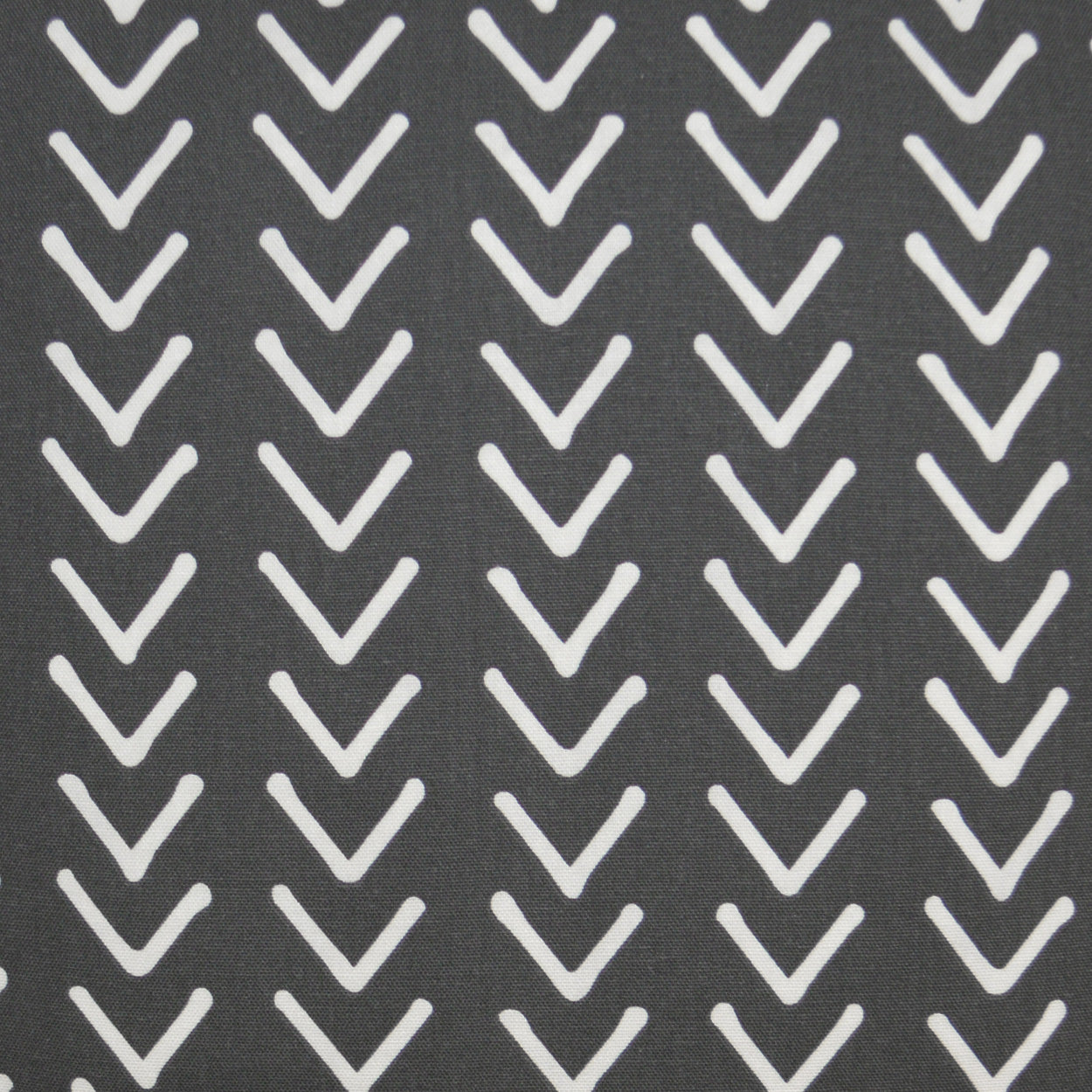 Dark gray fabric with repeating white chevron (V) motifs on a 24" x 24" pillow; modern geometric pattern.