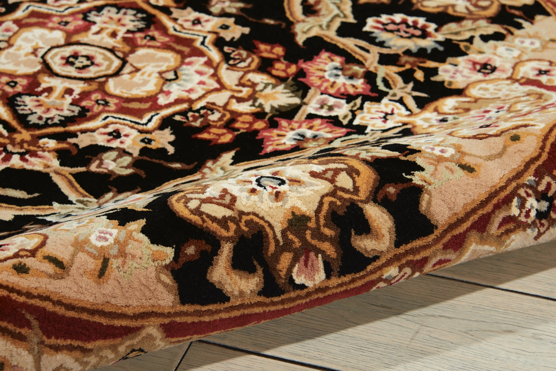 Intricately patterned oriental rug with floral motifs in browns, beiges and red, folded on a light wooden floor.