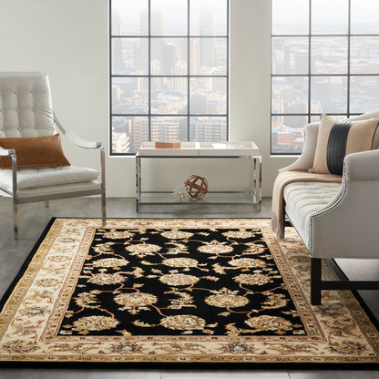 Rectangular oriental-style rug with black field, gold/ivory floral motifs, beige ornate border.
