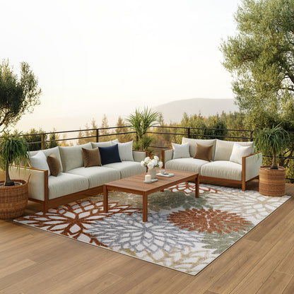 Outdoor sectional sofa set with beige cushions, wooden frame, colorful floral-patterned rug, wooden coffee table, potted plants on a deck.