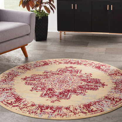 Round beige rug with a red oriental medallion pattern in a modern living room; gray sofa, black cabinet, potted plant.