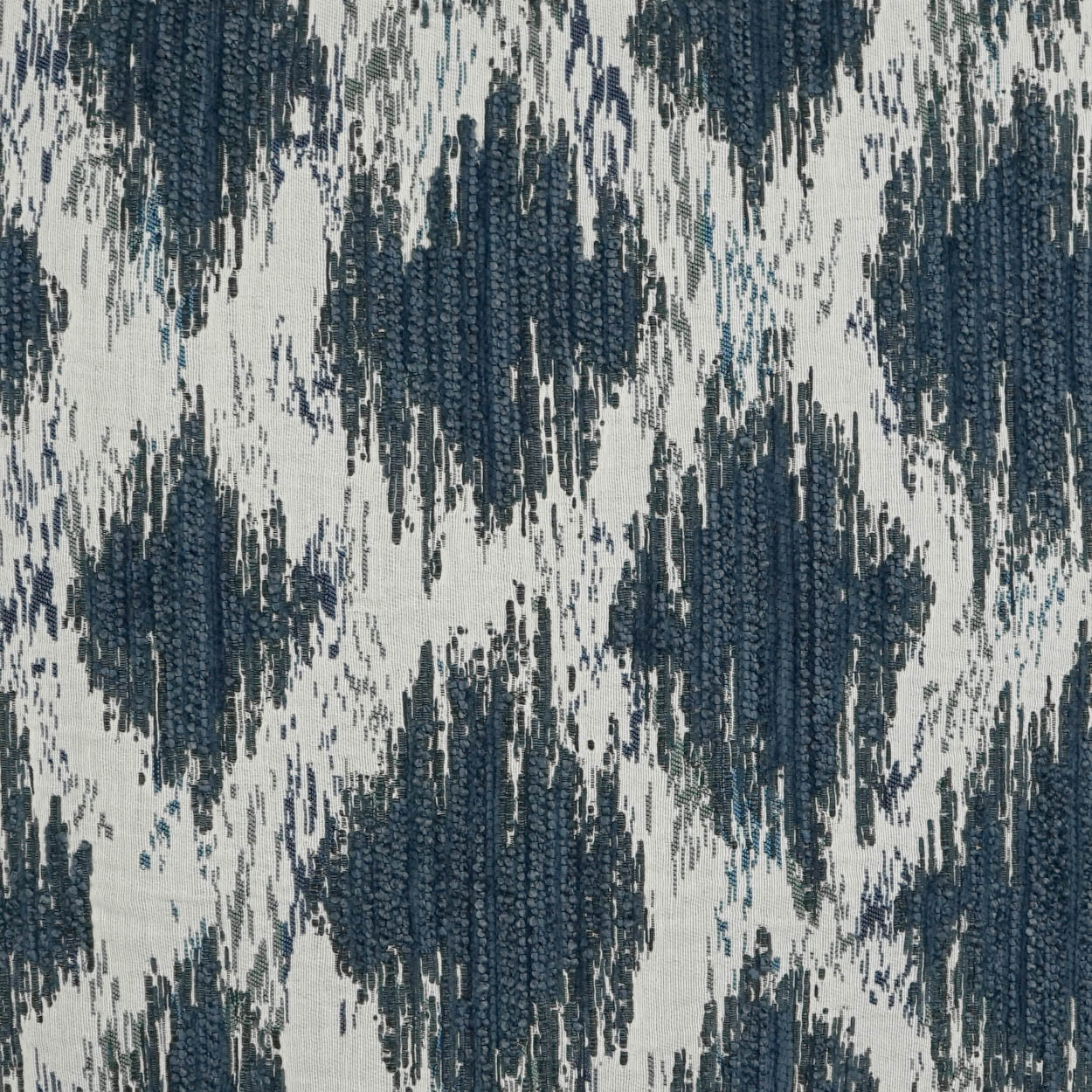 Ikat-inspired woven fabric in navy and blue on cream background; geometric diamond pattern for upholstery.
